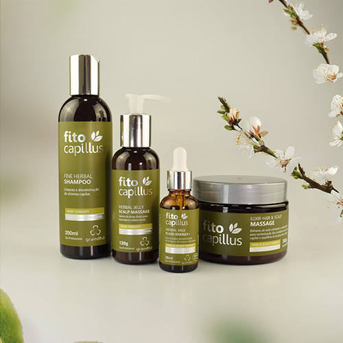 Linha de produtos Fito Capillus da Grandha para terapia capilar, exibindo shampoo, sérum e máscara ao lado de galhos floridos em fundo neutro.